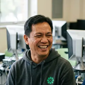 A teacher laughing in a computer lab, the Elevate Grade mark on his hoodie