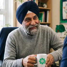 An educator talking with a colleague in a school office, holding an Elevate Grade mug